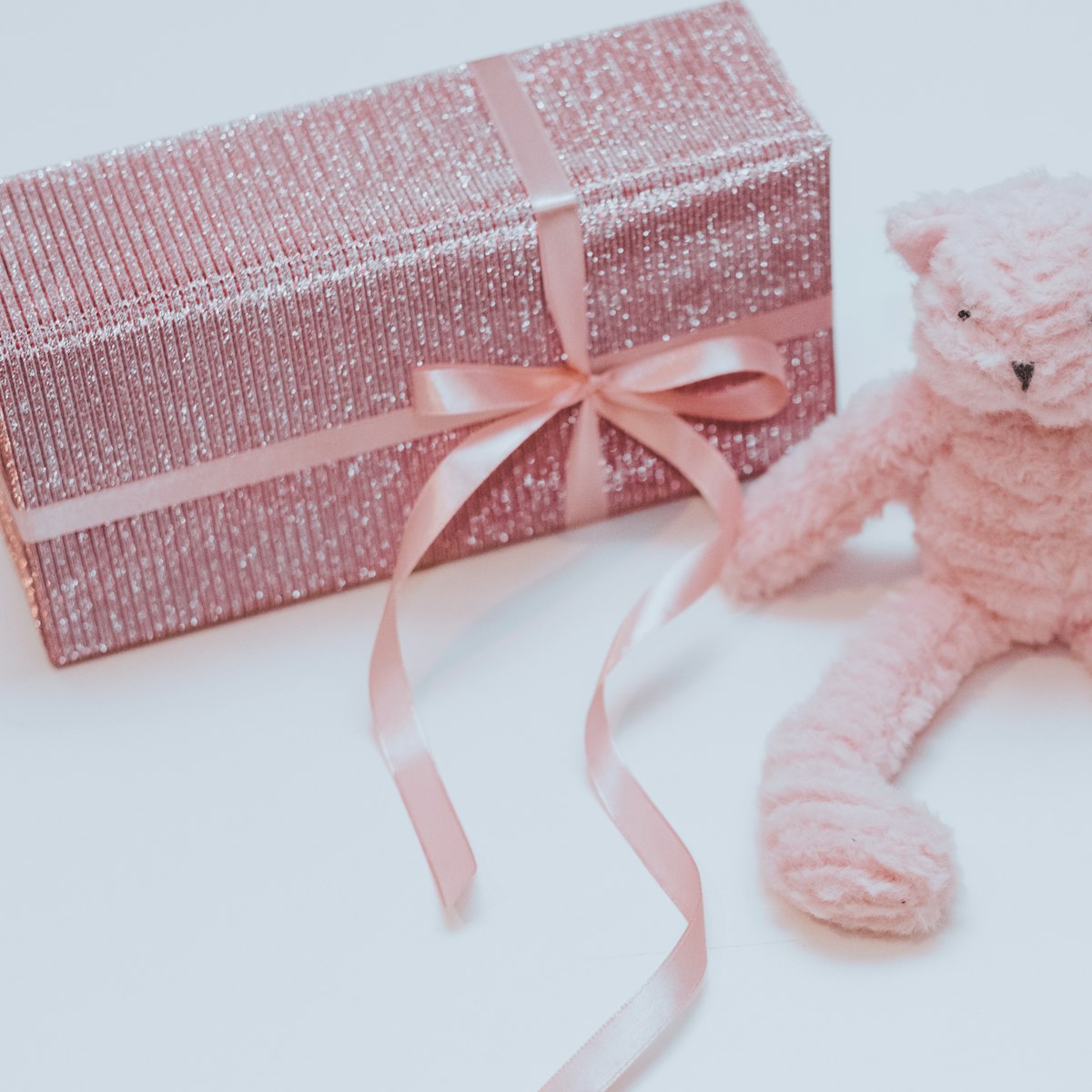 Pink teddy bear beside a gift box